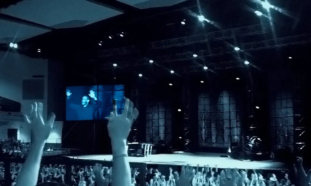A photo of some people in church with their hands in the air